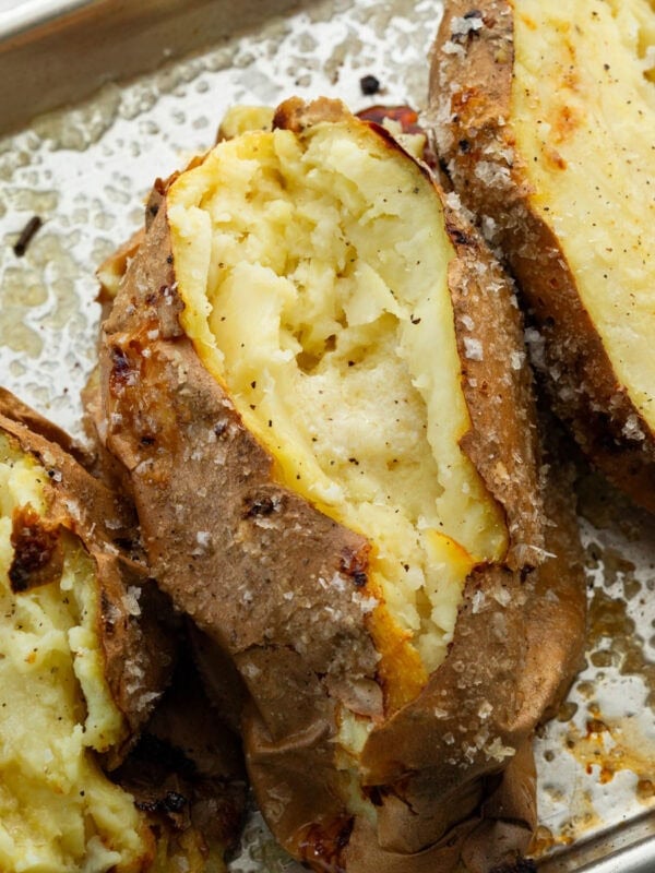 several baked white sweet potatoes that have been sliced open and fluffed inside