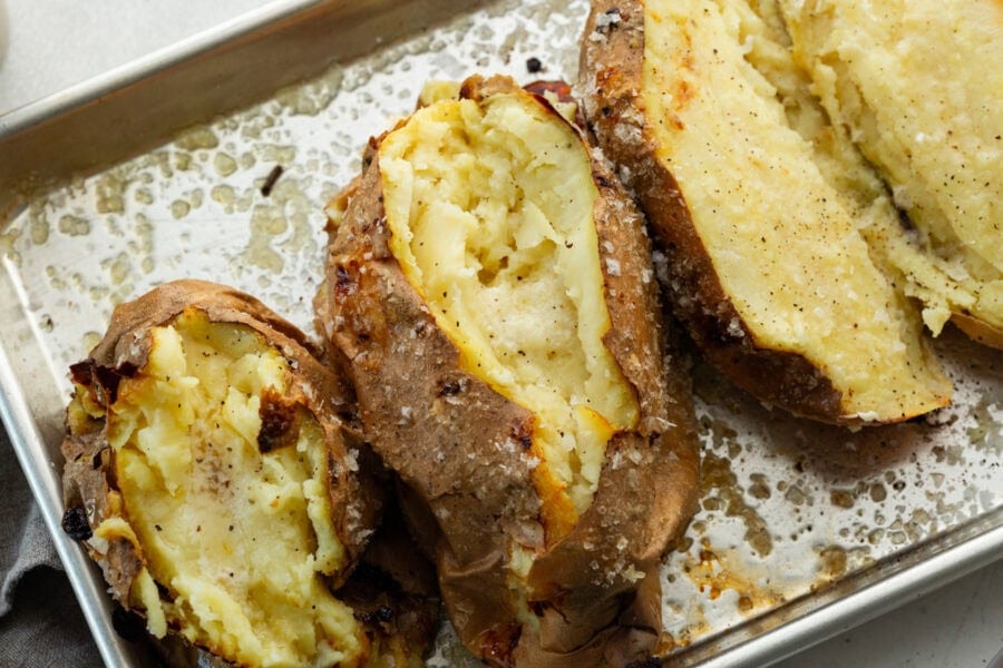 several baked white sweet potatoes that have been sliced open and fluffed inside