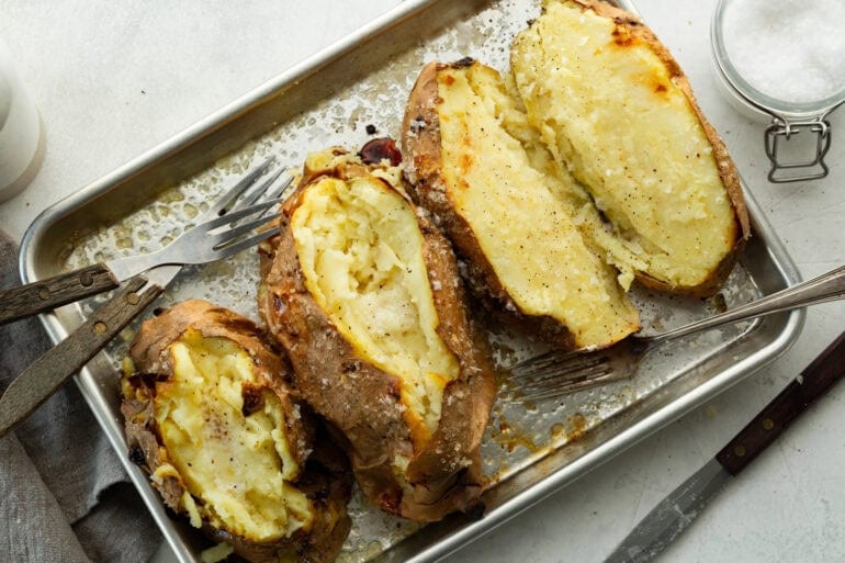 fluffy baked white sweet potatoes on a baking sheet and sprinkled with coarse sea salt