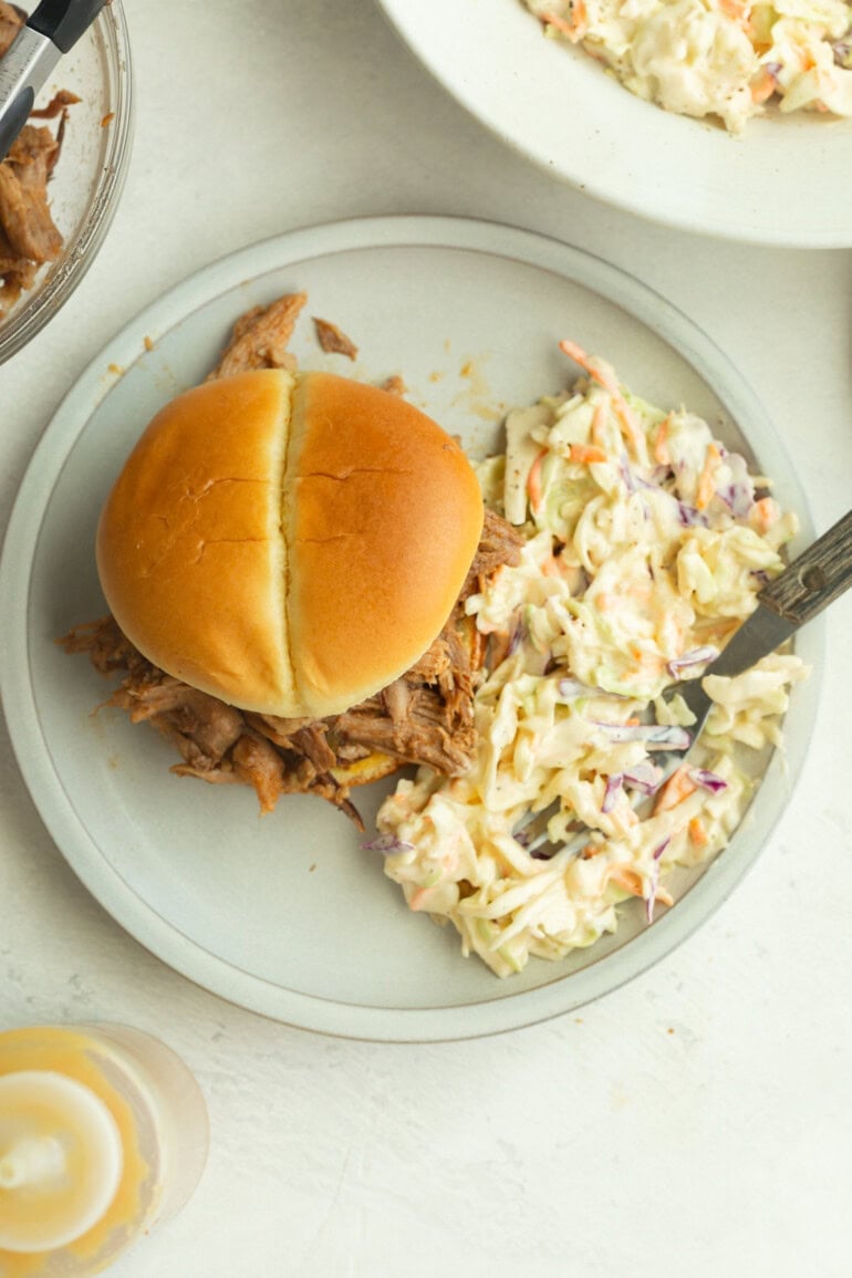 a bun with pulled pork with creamy summer slaw made with shredded green cabbage and carrots, dressed in a smooth, flavorful mixture.