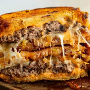a patty melt that is broken in half and stacked on each other so you can see the inside of the patty melt with melty cheese and juicy patties