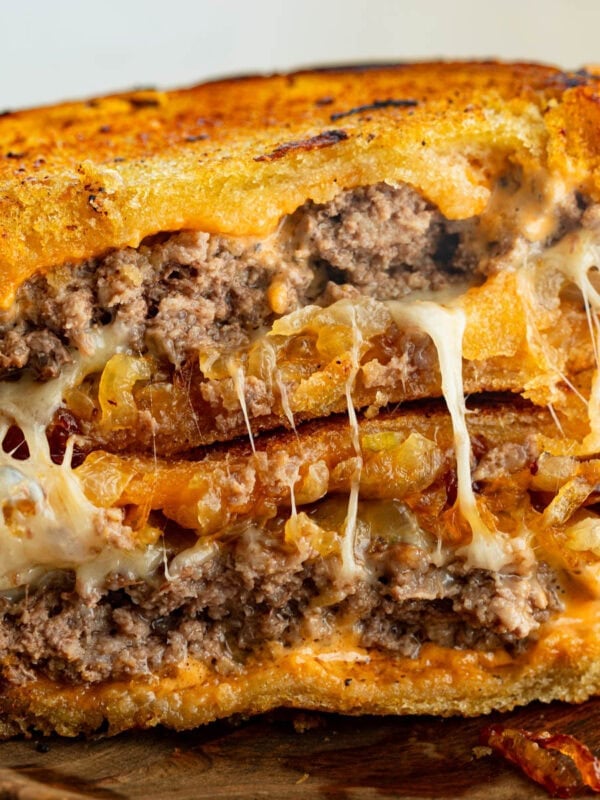 a patty melt that is broken in half and stacked on each other so you can see the inside of the patty melt with melty cheese and juicy patties