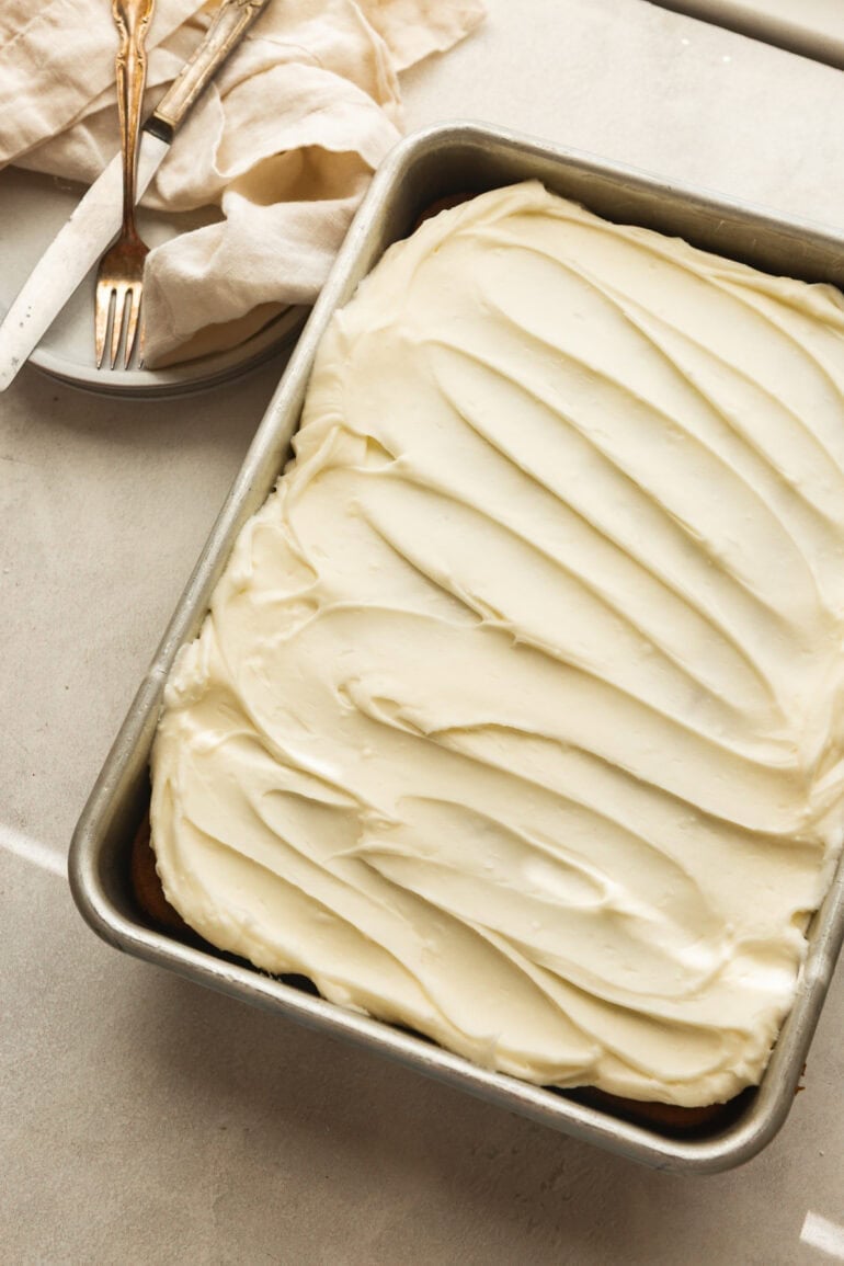 a 9x13 inch metal pan full of a pumpkin cake topped with cream cheese frosting