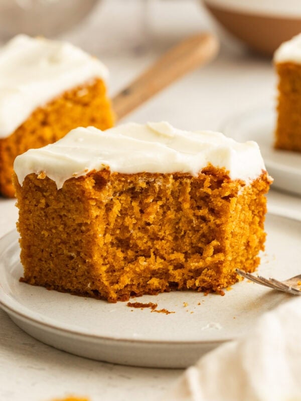 a piece of pumpkin cake topped with cream cheese frosting and a bite taken out of the corner