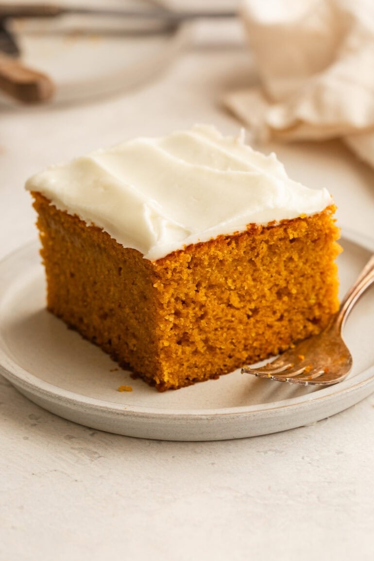 a slice of moist pumpkin cake with cream cheese frosting sitting on a small dessert plate