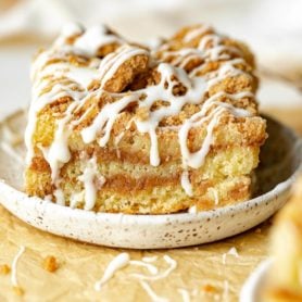 a photo of a single piece of coffee cake on a small saucer topped with a drizzle of icing.