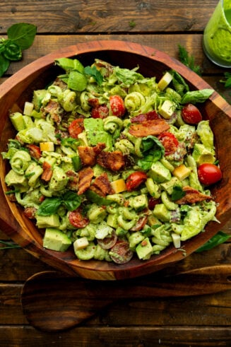 a photo of a large wooden serving bowl full of creamy blt pasta salad