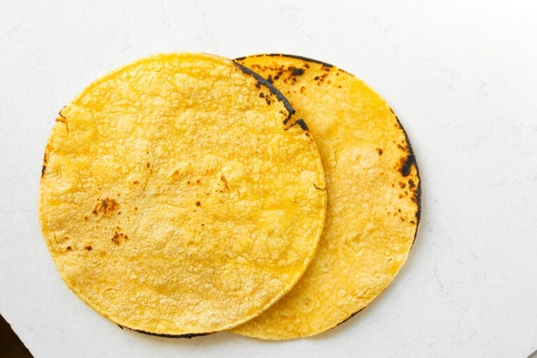 two cooked, slightly charred corn tortillas