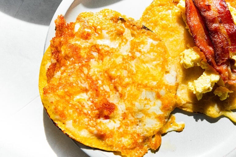 a corn tortilla covered in melted and slightly crispy cheese