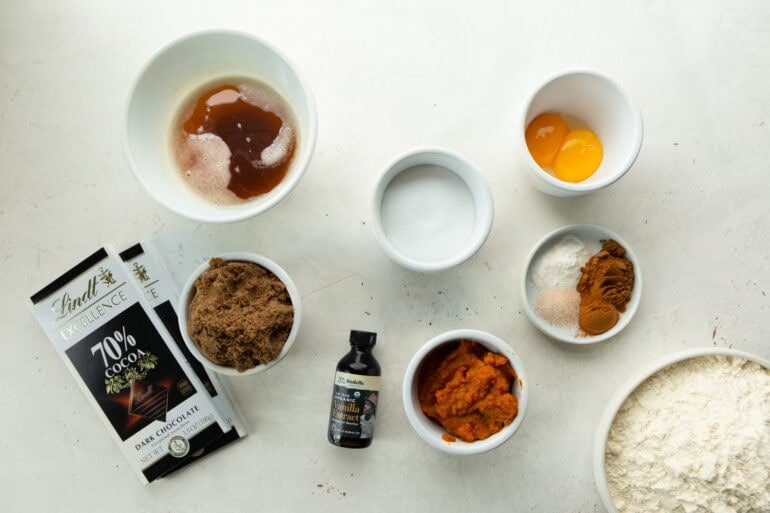Ingredients for pumpkin brown butter cookies including dark chocolate, vanilla, pumpkin, flour, brown butter, egg yolks, brown sugar, sugar, and spices.