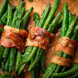 five bundles of green beans wrapped in a slice of bacon coated in caremlized brown sugar