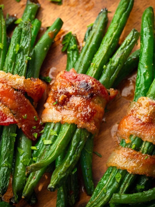 five bundles of green beans wrapped in a slice of bacon coated in caremlized brown sugar