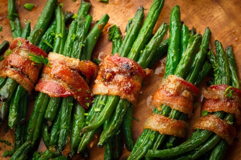 five bundles of green beans wrapped in a slice of bacon coated in caremlized brown sugar
