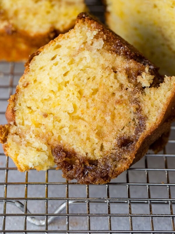 A photo of a slice of brown sugar bundt cake sitting on a wire cooling rack with a swirls of brown sugar and cinnamon in the middle.