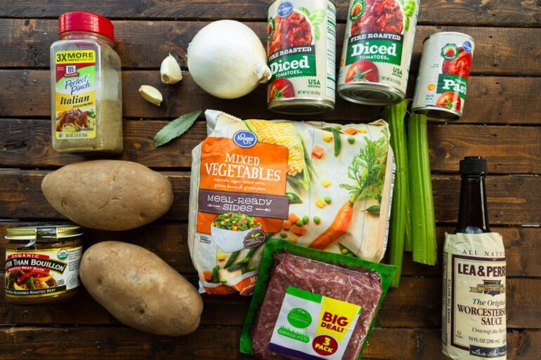 all the ingredients for ground beef vegetable soup including ground beef, potatoes, celery stalks, frozen mixed veggies, onion, garlic, diced tomatoes