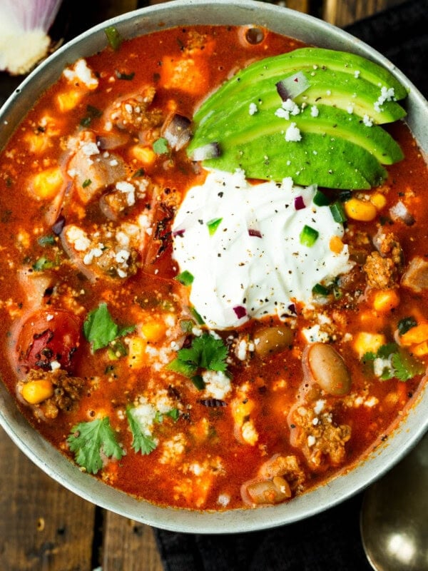 a bowl of charro bean soup topped with sour cream and sliced avocados