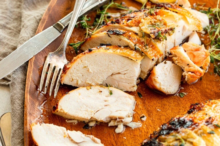 a roasted turkey breast that has sliced with one slice turned to show the cross section of the juicy turkey