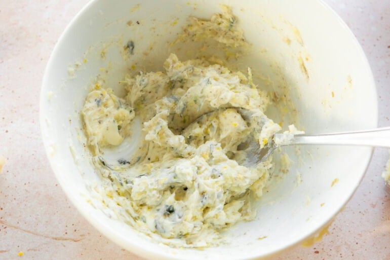 a bowl of herb butter being mixed with a spoon