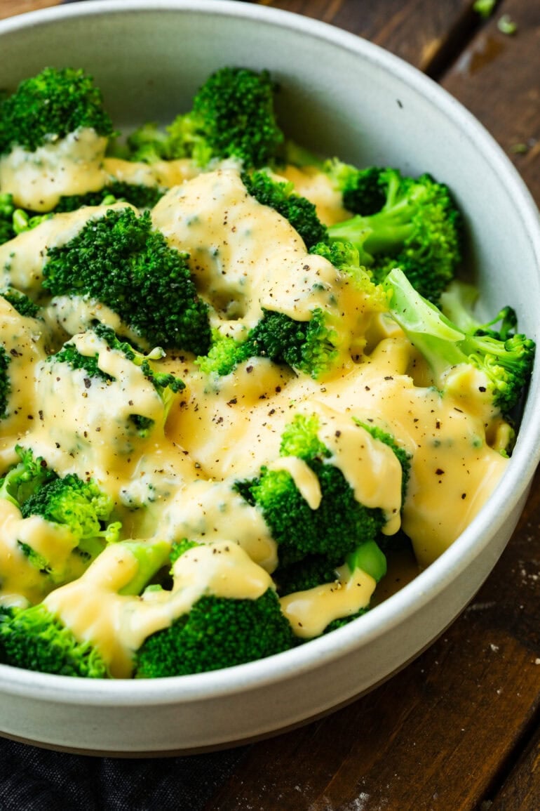 A photo of a large bowl of fresh steamed broccoli with cream cheese sauce and cracked pepper