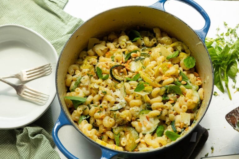 a large pot of cheesy creamy pasta mixed with cooked zucchini and yellow squash