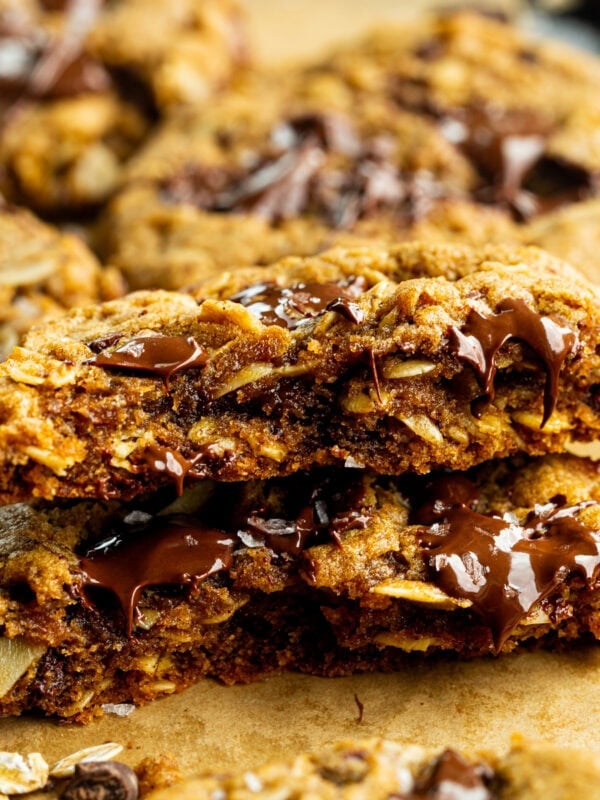 a thick and chewy pumpkin oatmeal cookie that has been broken in half and stacked on each other so you can see the inside of the cookie loaded with melty chocolate chunks