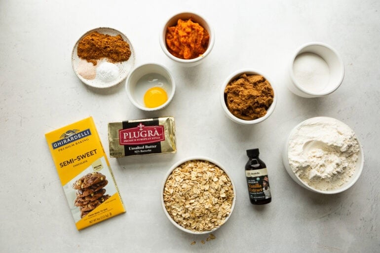 all the ingredients for pumpkin oatmeal chocolate chip cookies in separate small bowls and containers