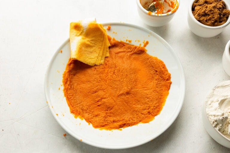 a white dinner plate topped with pumpkin puree that has been blotted with a paper towel to dry it out