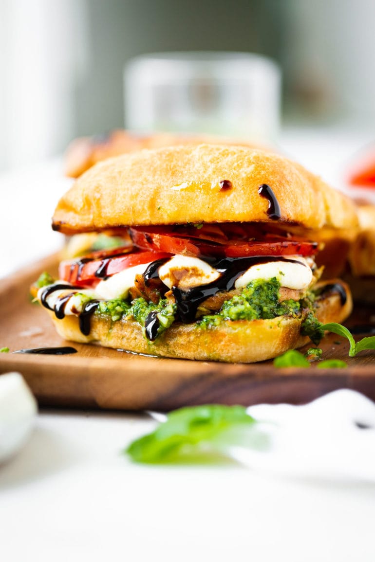 a photo of a chicken caprese sandwich on a ciabatta bun with tomato, fresh mozzarella, pesto and balsamic glaze.