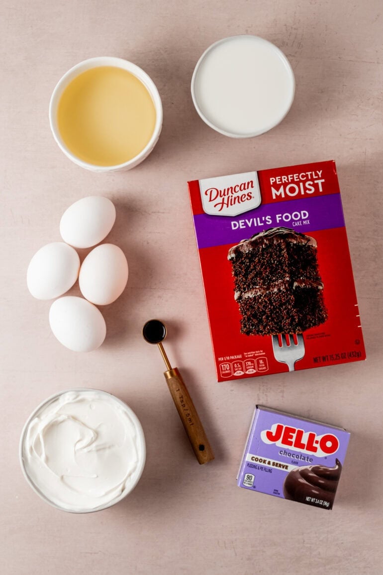 all the ingredients for a chocolate cake mix including a box mix for chocolate cake, a box of chocolate pudding, eggs, sour cream, vanilla and oil