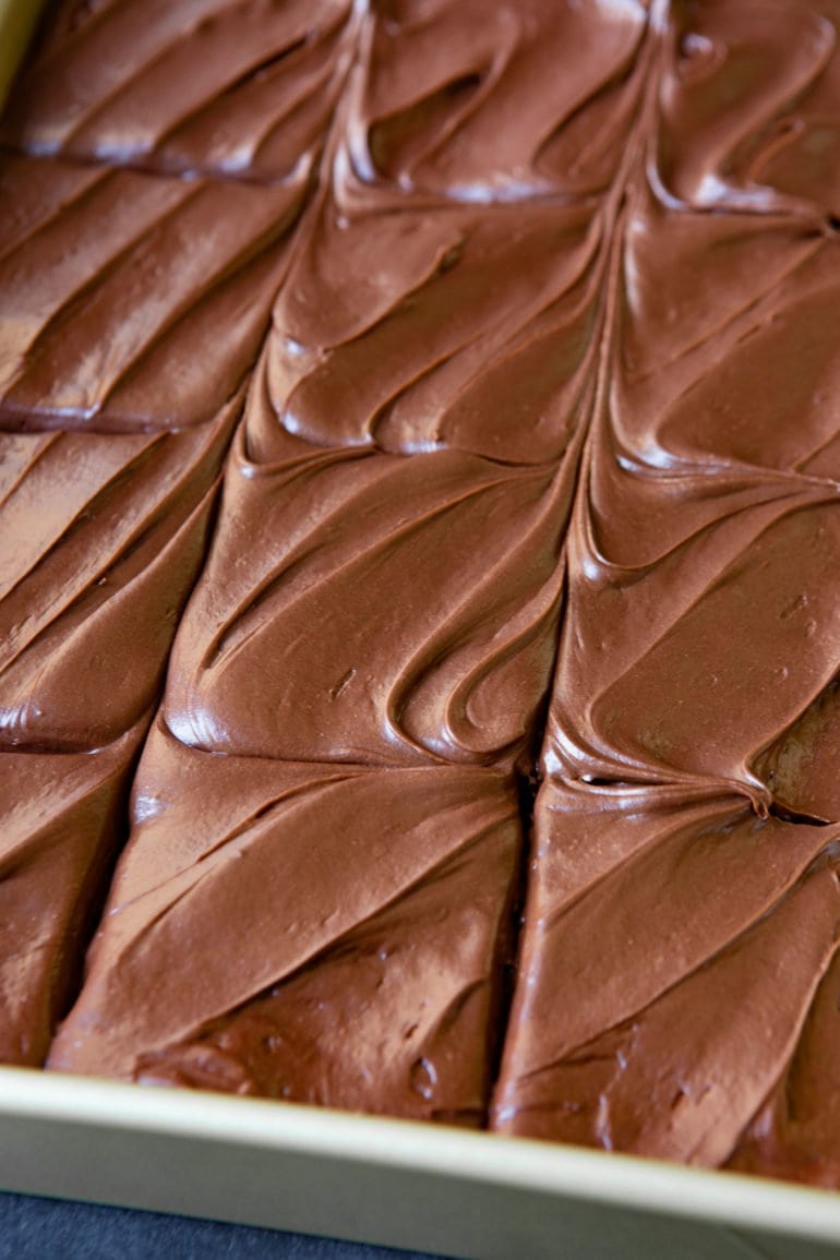 A top view of a moist chocolate zucchini cake with chocolate cream cheese frosting. The cake has been cut but not served.