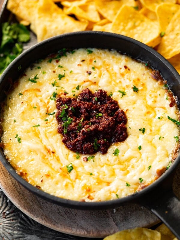 a photo of a small cast iron skillet full of golden bubbly queso fundido with a pile of cooked chorizo in the middle.