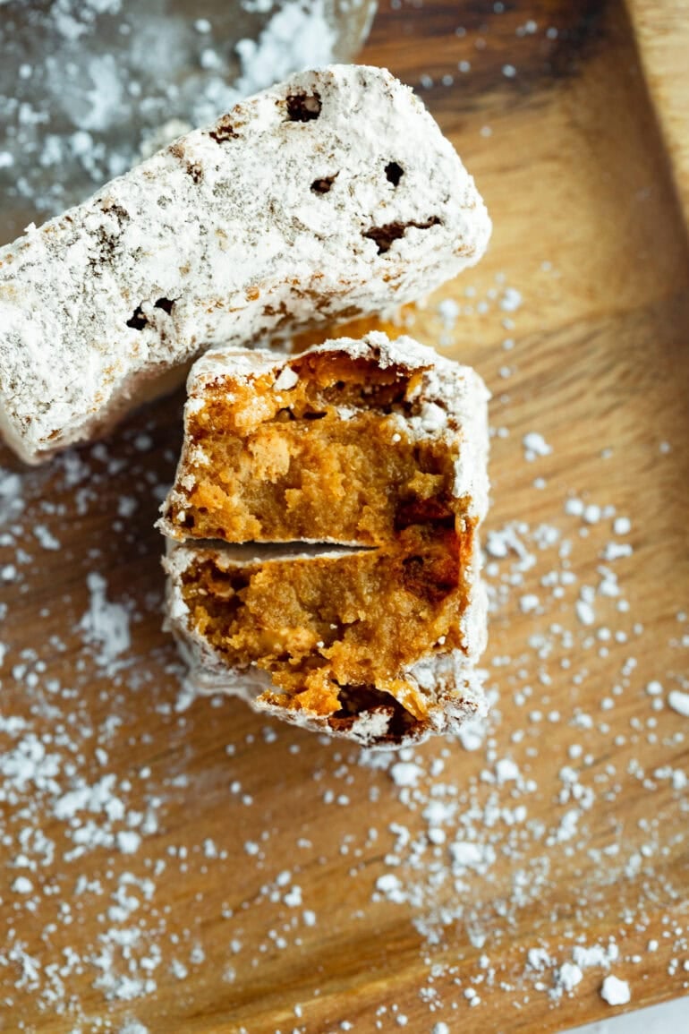a peanut butter bar coated in powdered sugar broken in half and turned on end so you can see the inside of each gooey bar