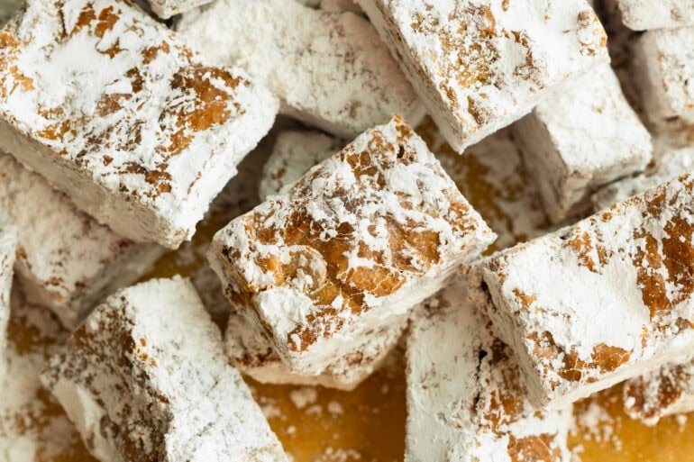 several chubby hubby peanut butter bars coated in powdered sugar sitting on brown parchment paper