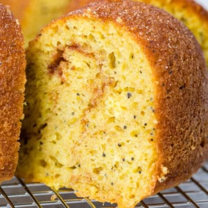 A photo of a slice of cinnamon lemon poppy seed bundt sitting on a wire cooling rack.