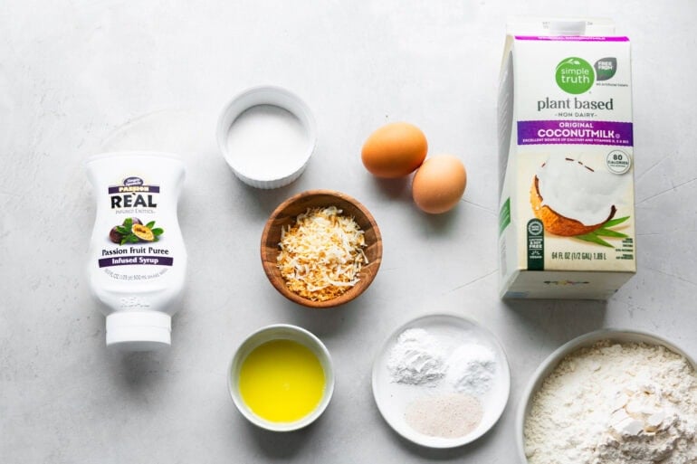 all the ingredients for coconut pancakes including coconut milk, eggs, flour, melted butter, toasted coconut, etc all in separate small bowls