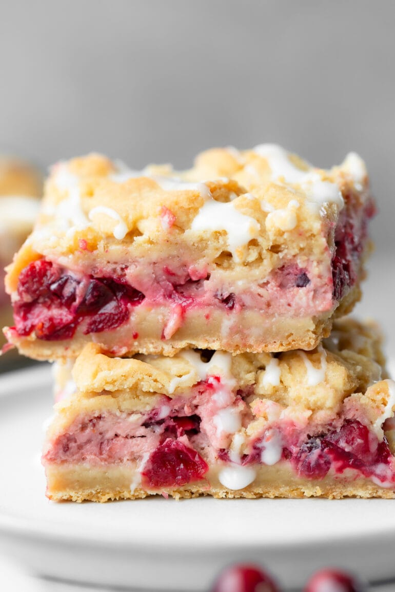 a photo of two cranberry crumb bars stacked on each other on a small dessert plate