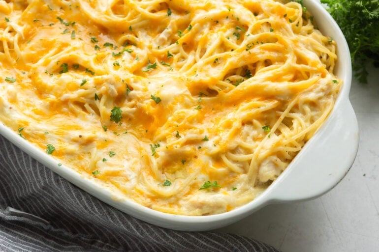 Close-up of cream cheese chicken noodle casserole showing tender noodles and creamy sauce in a white ceramic pan.
