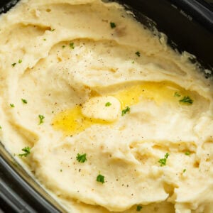 Creamy crockpot mashed potatoes topped with melted butter and fresh herbs