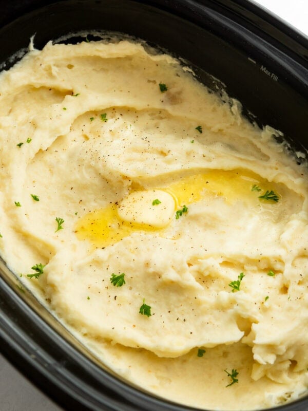 Creamy crockpot mashed potatoes topped with melted butter and fresh herbs