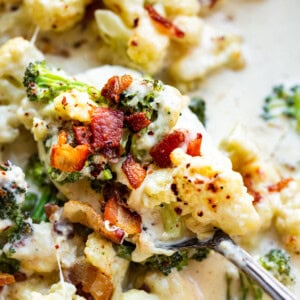 a photo of someone scooping out a bite of creamy garlic parmesan broccoli and cauliflower