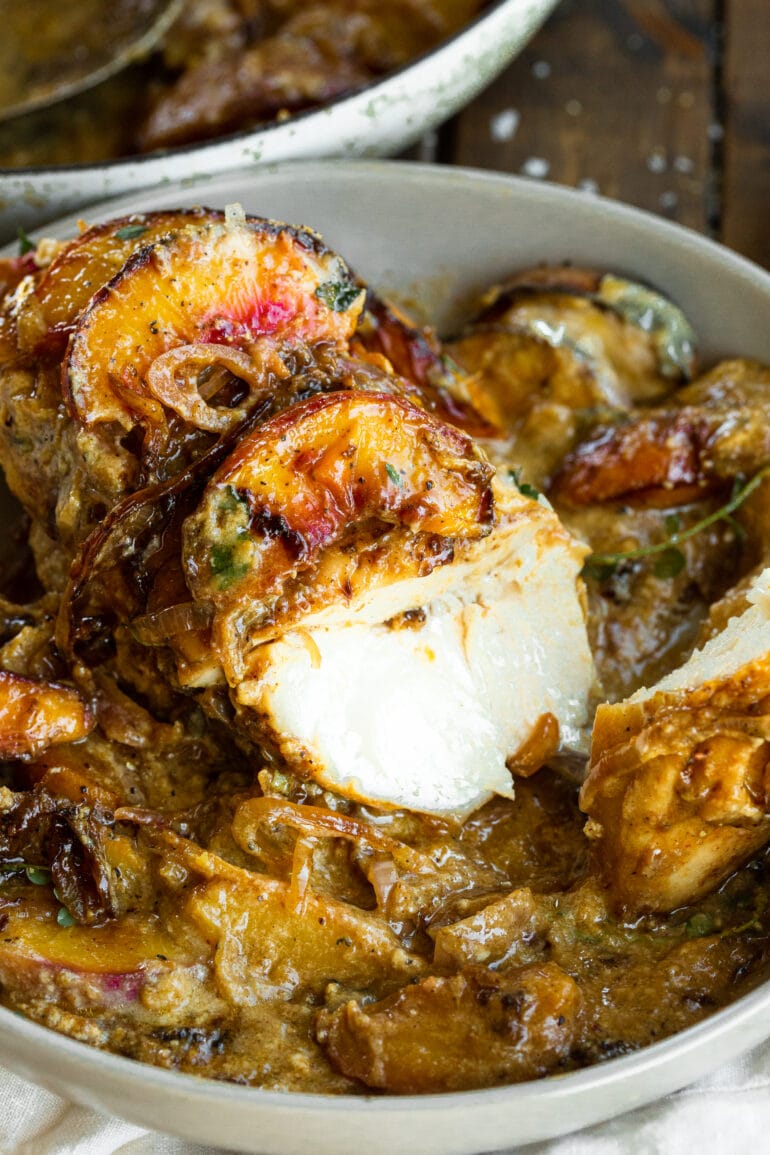 a photo of a bowl of baked chicken covered in a creamy sauce with one chicken breast cut open so you can see the juicy center