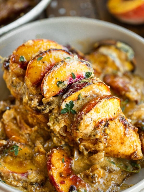 a photo of a baked chicken breast topped with sliced fresh peaches and a creamy sauce