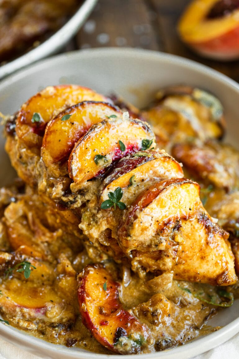a photo of a baked chicken breast topped with sliced fresh peaches and a creamy sauce