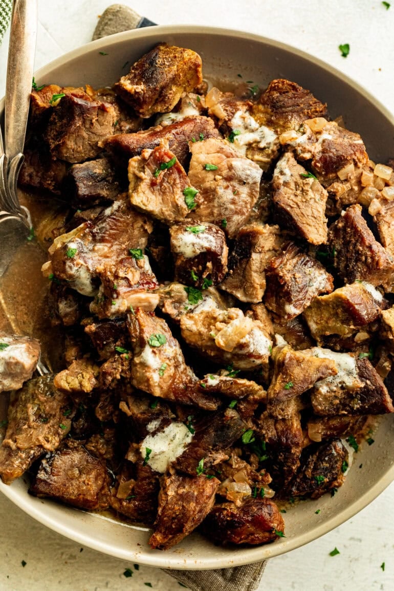 juicy steak bites coated in garlic butter mixed with diced onions and sprinkled with chopped fresh parsley