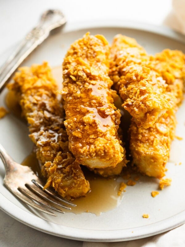 a stack of crunch french toast sticks sitting on a plate covered in syrup