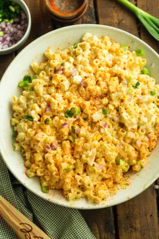 a photo of a large serving bowl of creamy deviled egg pasta salad topped with chopped chives