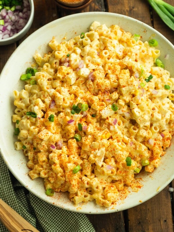 a photo of a large serving bowl of creamy deviled egg pasta salad topped with chopped chives