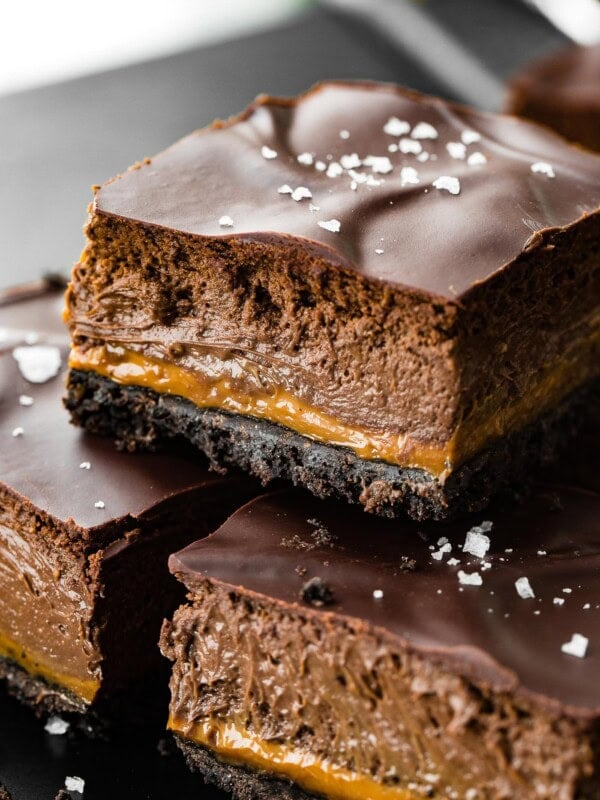 a layered chocolate cheesecake bar with whipped ganache on top