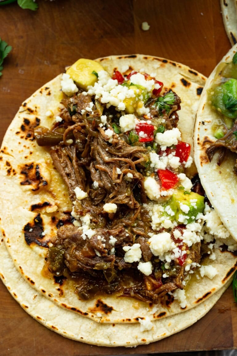 Shredded poblano braised beef tucked into a warm corn tortilla and topped with avocado, salsa, queso fresco, and fresh cilantro.