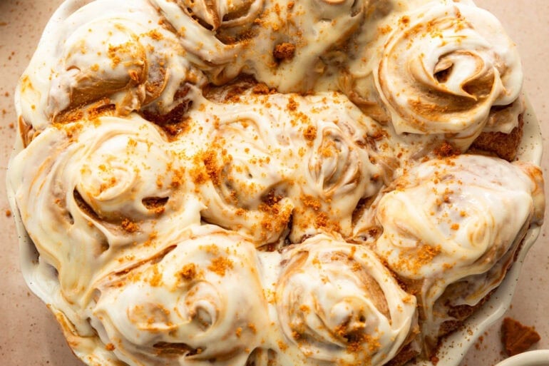 Pan of Biscoff cinnamon rolls topped with swirled cookie butter cream cheese frosting